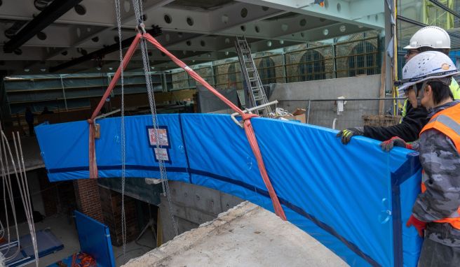 Mitarbeiter einer Spezialfirma transportieren auf der Baustelle des Meeresmuseums eine über sechs Meter lange Acrylglasscheibe aus Japan.