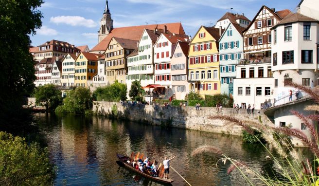 Der Bootsführer im Stocherkahn erklärt Touristen die Neckarfront in Tübingen. 