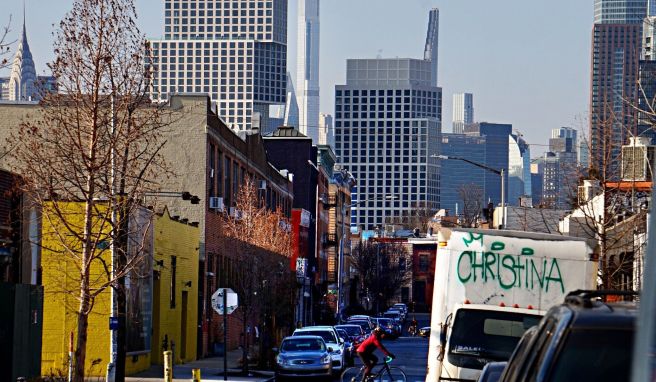 Ein Fahrradfahrer radelt durch Greenpoint Brooklyn, im Hintergrund ist Midtown Manhattan zu sehen. Auf dem Rad erfährt man die Energie von New York City auf eine besondere Weise.