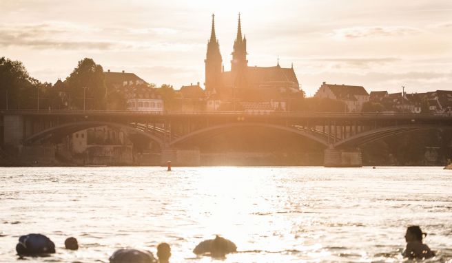 Panoramablick aufs Münster: Menschen treiben mit ihrem Wickelfisch in Basel den Rhein hinab. 