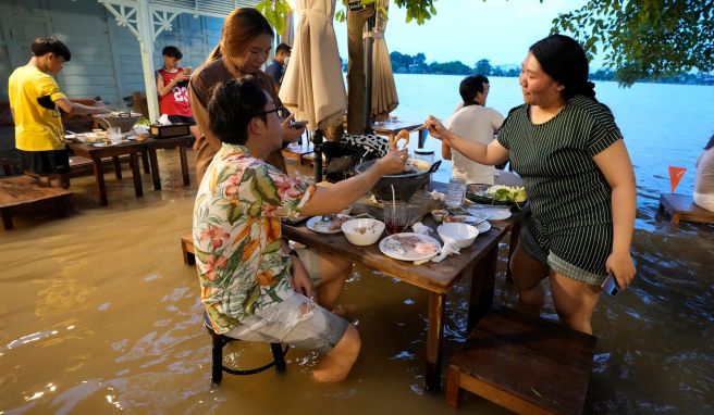 Menschen sitzen trotz des hohen Wasserstands im «Chaopraya Antique Café». Das von der Flutkatastrophe betroffene Restaurant hat sich zu einem Hotspot entwickelt. 