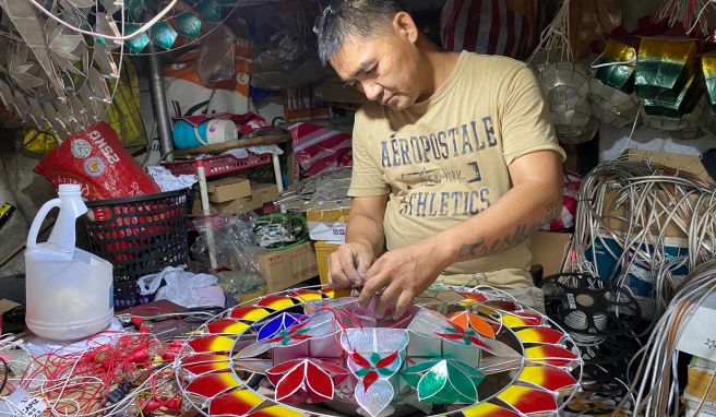 Andrew Flores fügt in seinem kleinen Geschäft für Weihnachtsdekoration im Dorf Elias Aldana nahe Manila Glühbirnen zu einer aus Capiz-Muscheln gefertigten Parole hinzu. 