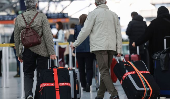 Ältere Reisende gehen am Flughafen mit Reisekoffern durch das Terminal.