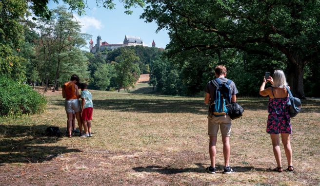 Touristen fotografieren die Veste Coburg vom Hofgarten aus. Der Tourismus in Bayern hat fast wieder Vor-Corona-Niveau erreicht.