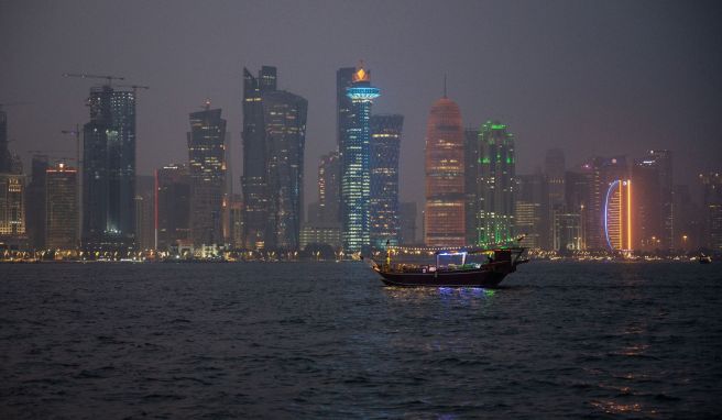 Ein traditionelles Holzschiff, Dhow genannt, fährt am Abend in der Bucht vor der katarischen Hauptstadt Doha.