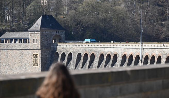 Eine Frau läuft über die Sperrmauer des Edersees. Das neue Besucherzentrum am Edersee informiert über Angebote und Aktivitäten in der Region.