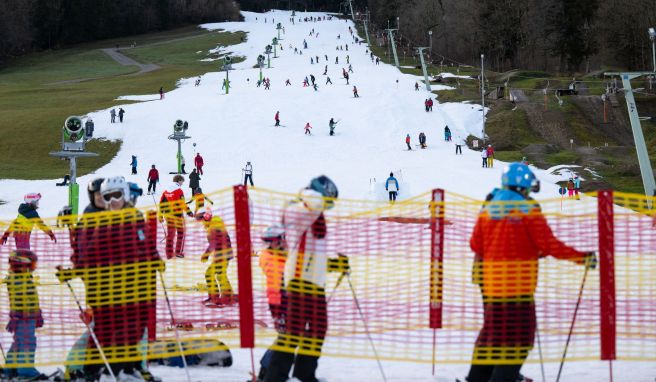 Wintersportler stehen am Streidhang im Skigebiet Brauneck an einem Lift an. Viele Skigebiete in Bayern leiden aktuell unter Schneemangel.