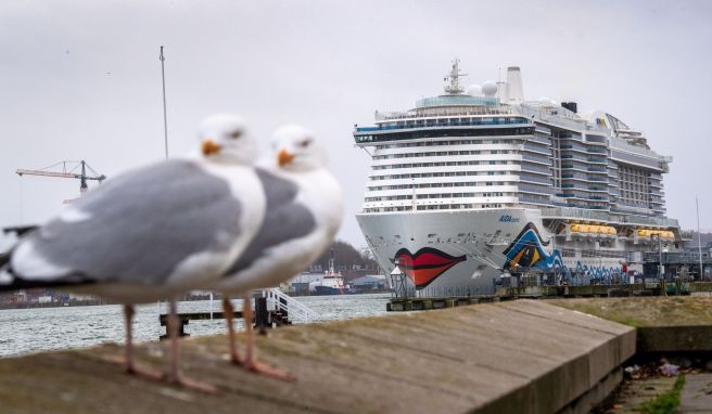 Passagiere verfolgen an Bord eines Kreuzfahrtschiffs das Auslaufen aus dem Hafen. 