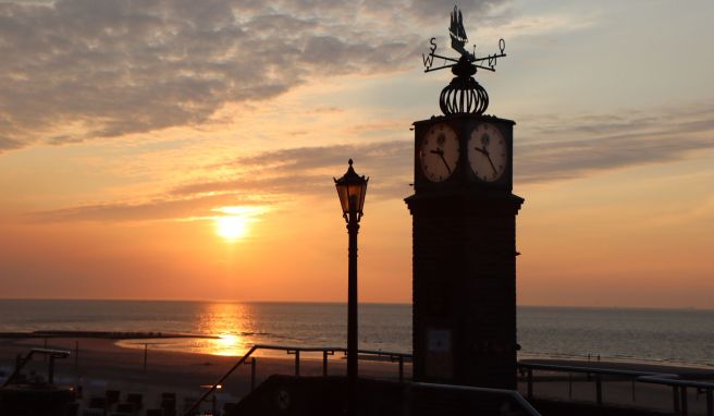 Die Sonne geht hinter der sogenannten Puddinguhr an der Strandpromenade der Insel Wangerooge unter. An den längsten Tagen des Jahres locken einige Ostfriesische Inseln ihre Gäste mit Kultur- und Freizeitangeboten.