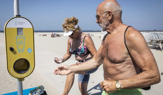 Ein Spender mit kostenlosem Sonnenschutz steht an einem niederländischen Strand, um Besucher vor Sonnenbrand zu schützen.