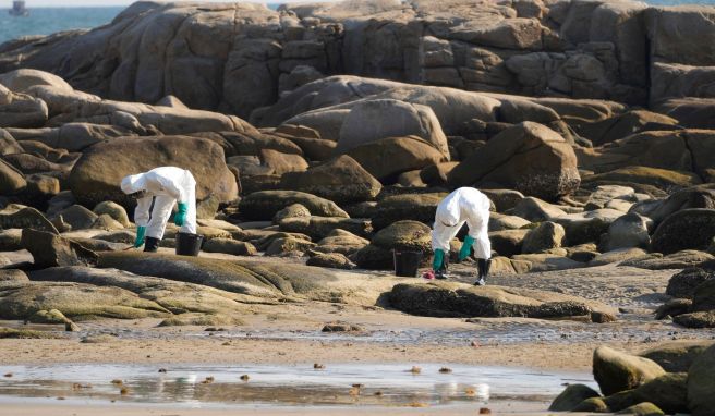 Arbeiter schrubben Öl von den Felsen am Strand von Mae Ramphueng, nachdem eine Ölpipeline vor der Küste der Provinz Rayong im Osten Thailands ausgelaufen war. 