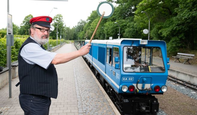 Uwe Schneider, Mitarbeiter der Parkeisenbahn Dresden, hebt am Hauptbahnhof die grüne Kelle zur Abfahrt. 