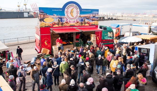 Besucher stehen am Morgen auf dem Hamburger Fischmarkt an der Elbe an einem Verkaufsstand. Vor den Ständen der Marktschreier bilden sich häufig große Menschenansammlungen. 