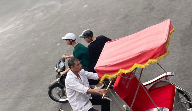 Ein Rikschafahrer ist in Hanois Altstadt unterwegs auf der Suche nach Kunden. 