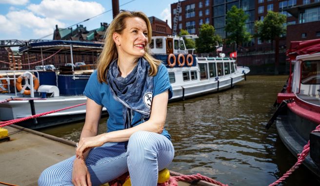 Tourguide Maike Brunk sitzt vor einer Tour durch den Hamburger Hafen vor einer Barkasse. 