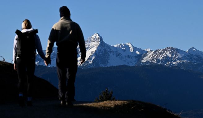 Verschneit zeigt sich der Gipfel des Daniel vor zwei Wanderern. In den deutschen Alpen sind zur Jahreswende weniger Touristen angekommen als vor der Corona-Pandemie.
