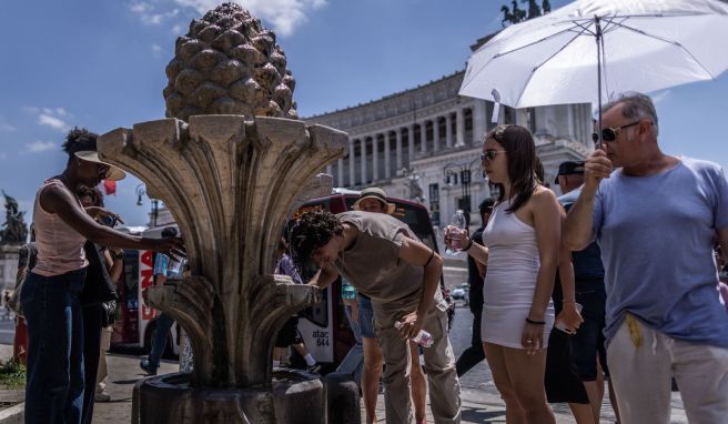 Schirm als Schutz: Touristen in der sengenden Sonne auf der Piazza Venezia in Rom.