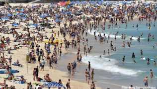 Strandbesucher liegen am Bondi Beach und genießen das sonnige Wetter Strandbesucher liegen am Bondi Beach und genießen das sonnige Wetter
