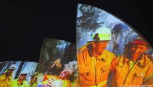 Auf den großen Segeln des Opernhauses werden als Dank und Zeichen der Solidarität Bilder von Feuerwehrleuten auf die großen Segel der Oper in Sydney projiziert Auf den großen Segeln des Opernhauses werden als Dank und Zeichen der Solidarität Bilder von Feuerwehrleuten auf die großen Segel der Oper in Sydney projiziert