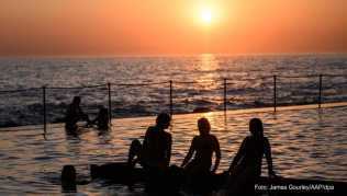 Schwimmer verfolgen den Sonnenaufgang am Bronte Beach Pool vom Ocean-Pool aus. Das Schwimmen und Baden in Meerwasser-Pools hat in Australien Tradition Schwimmer verfolgen den Sonnenaufgang am Bronte Beach Pool vom Ocean-Pool aus. Das Schwimmen und Baden in Meerwasser Pools hat in Australien Tradition