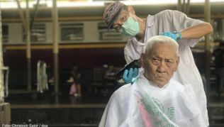 Auf dem Hauptbahnhof Hua Lamphong schneidet ein Friseur einem älteren Mann die Haare. Der Haarschnitt ist kostenlos Auf dem Hauptbahnhof Hua Lamphong schneidet ein Friseur einem älteren Mann die Haare. Der Haarschnitt ist kostenlos