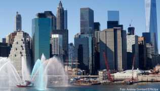 Ein Feuerwehrboot verspritzt Wasser in bunten Farben auf dem East River vor der Skyline von Lower Manhattan. Die Downtown Alliance sucht für die Südspitze Manhattans einen Chef-Entdecker Ein Feuerwehrboot verspritzt Wasser in bunten Farben auf dem East River vor der Skyline von Lower Manhattan. Die Downtown Alliance sucht für die Südspitze Manhattans einen Chef-Entdecker