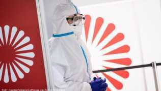Eine Mitarbeiterin in Schutzanzug wartet im neuen, kommerziellen Covid-19-Testzentrum am Flughafen Hamburg auf Reisende Eine Mitarbeiterin in Schutzanzug wartet im neuen, kommerziellen Covid-19-Testzentrum am Flughafen Hamburg auf Reisende