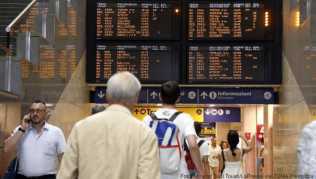 Reisende gehen unter einer Fahrplananzeige am Mailänder Hauptbahnhof Reisende gehen unter einer Fahrplananzeige am Mailänder Hauptbahnhof