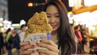 Knuspriger Snack: Eine Besucherin des Shilin Night Market in Taipeh hat sich frittiertes Hähnchen gekauft Knuspriger Snack: Eine Besucherin des Shilin Night Market in Taipeh hat sich frittiertes Hähnchen gekauft