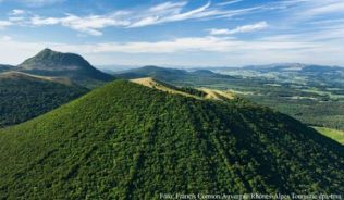 Der Blick auf grüne Vulkankegel begeistert Wanderer auf dem Weg zum Gipfel des Puy de Dôme (im Hintergrund)##Foto: Francis Cormon/Auvergne-Rhônes-Alpes Tourisme/dpa-tmn Der Blick auf grüne Vulkankegel begeistert Wanderer auf dem Weg zum Gipfel des Puy de Dôme (im Hintergrund)