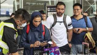 Sicherheitsbeamte überprüft die Bordkarten von Passagieren in Hongkong, bevor diese in das Flughafen-Terminal gelassen werden Sicherheitsbeamte überprüft die Bordkarten von Passagieren in Hongkong, bevor diese in das Flughafen-Terminal gelassen werden