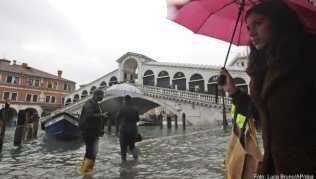 Passanten gehen in der Nähe der Rialto-Brücke durch das Hochwasser Passanten gehen in der Nähe der Rialto-Brücke durch das Hochwasser