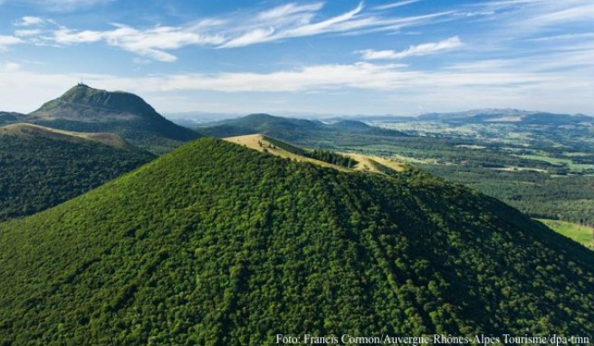 Der Blick auf grüne Vulkankegel begeistert Wanderer auf dem Weg zum Gipfel des Puy de Dôme (im Hintergrund)