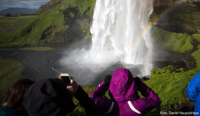 Touristen schauen sich am den Wasserfall »Seljalandsfoss« in der Gemeinde Rangarping eystra in Island an. Nach wachsenden Touristenmassen droht in Island die Stimmung gegenüber Urlaubern zu kippen.