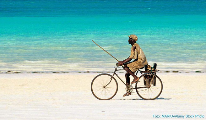 Radfahrer unterwegs am weißen Strand von Kiwengwa
