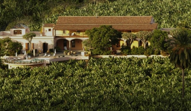 Ein historisches ockerfarbenes 18-Zimmer-Haus mit Torbögen, Terrassen und Poolterrasse inmitten von Bananenplantagen