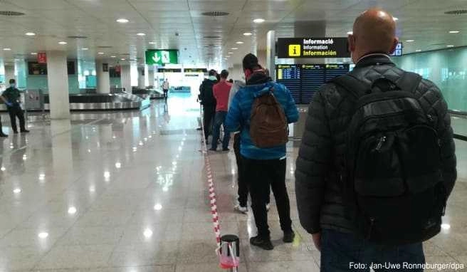 In einer langen Schlange stehen Einreisende aus dem Ausland im Terminal 1 des Flughafens in Barcelona vor der Gesundheitskontrolle zur Temperaturmessung an In einer langen Schlange stehen Einreisende aus dem Ausland im Terminal 1 des Flughafens in Barcelona vor der Gesundheitskontrolle zur Temperaturmessung an