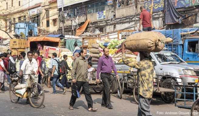 Kalkutta ist eine belebte Stadt. Nahe der Howrah Bridge teilen sich Fußgänger, Autofahrer und Händler die Straße