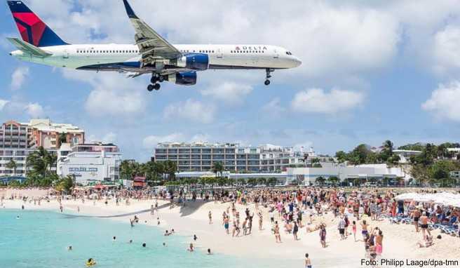 Flugzeug im Landeanflug über dem Maho Beach auf der Karibikinsel St. Martin - der Tourismus mit seinen Flugreisen trägt selbst zum Klimawandel bei