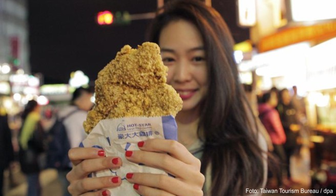Knuspriger Snack: Eine Besucherin des Shilin Night Market in Taipeh hat sich frittiertes Hähnchen gekauft
