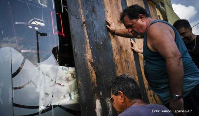 Männer auf Puerto Rico verbarrikadieren die Fenster eines Ladens. Sie bereiten sich damit auf das Eintreffen des Tropensturms »Dorian« vor