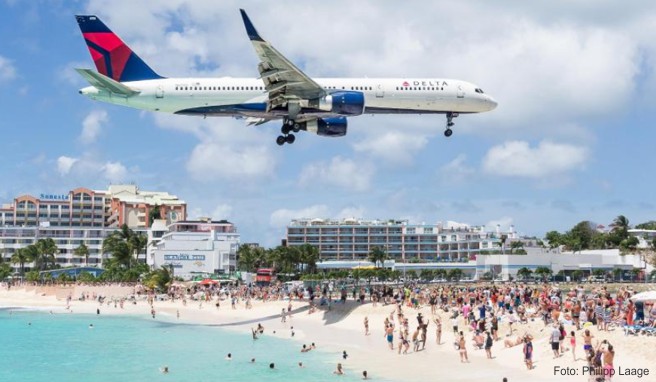 Urlauber beobachten im März 2016 am Maho Beach auf dem niederlaendischen Teil der Insel St. Martin ein landendes Flugzeug der Fluggesellschaft Delta