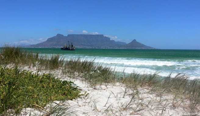 Spazieren am Strand, im Hintergrund der Tafelberg: So lässt es sich in Südafrika urlauben