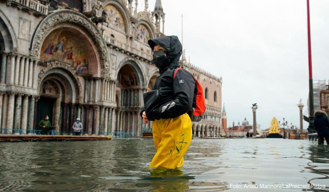 Eine Passantin bahnt sich ihren Weg durch den überfluteten Markusplatz. Starke Regenfälle haben in Venedig Teile der Stadt überflutet