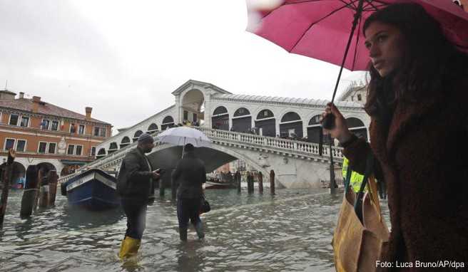 Passanten gehen in der Nähe der Rialto-Brücke durch das Hochwasser